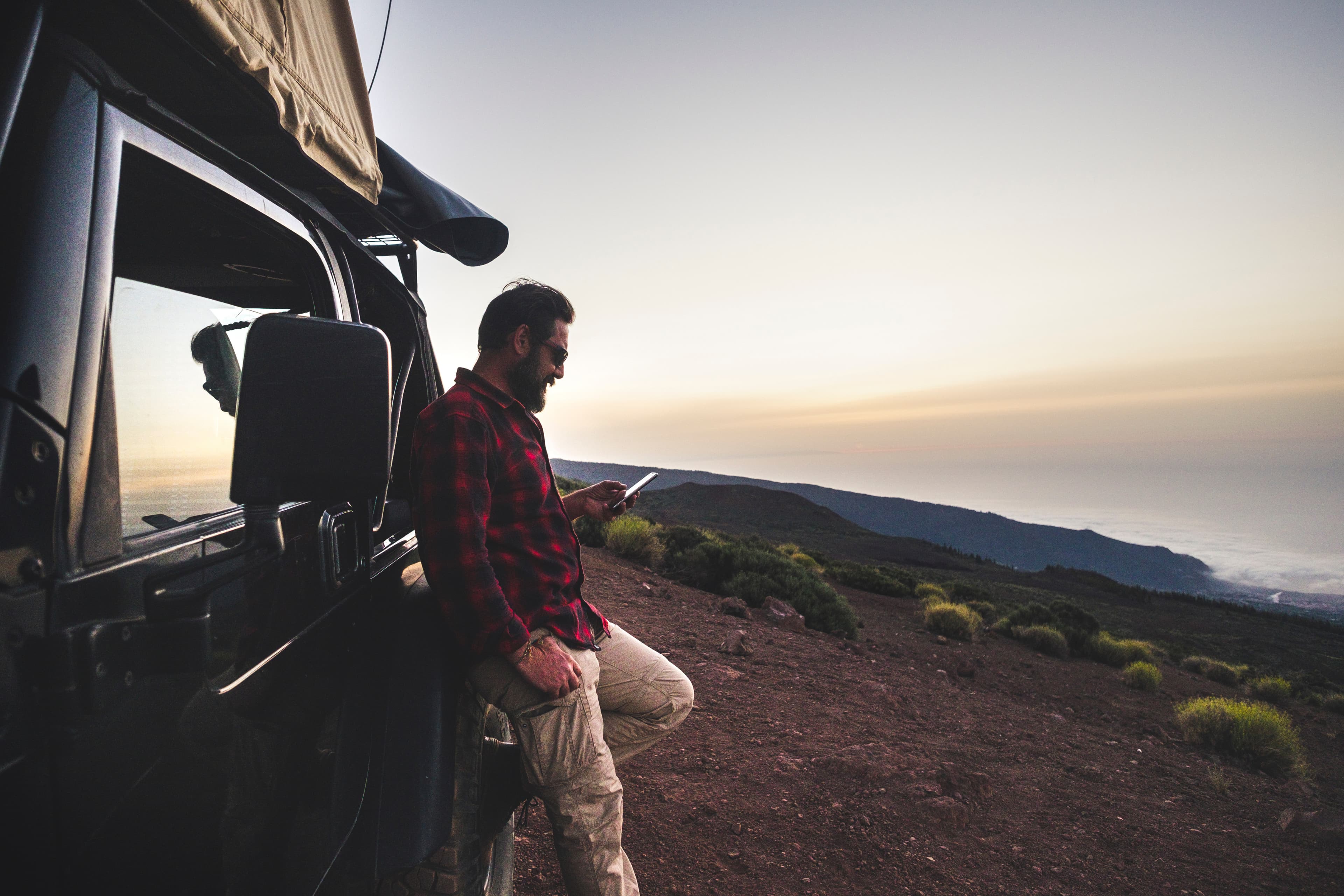 Man using a phone outdoors with mountains in the background